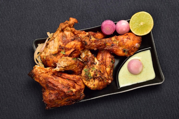Vista superior del pollo tandoori con chutney y cebolla en plato, famosa comida india tandoori murga