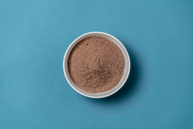 Una vista superior del polvo de cacao dulce marrón en un tazón blanco