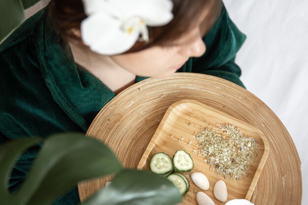 Vista superior, prato com fatias de pepino frescas e sal marinho nas mãos femininas, conceito de procedimentos de spa, cuidados com a pele.