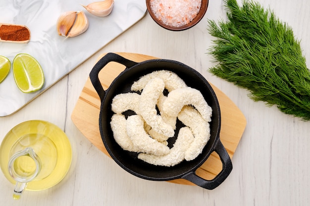 Vista superior del preparado para freír camarones crudos en empanizado de queso con especias