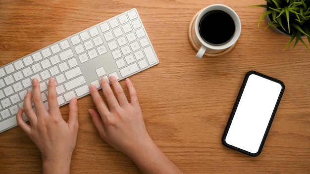 Vista superior de primer plano de las manos de una niña escribiendo en el teclado de la computadora de escritorio