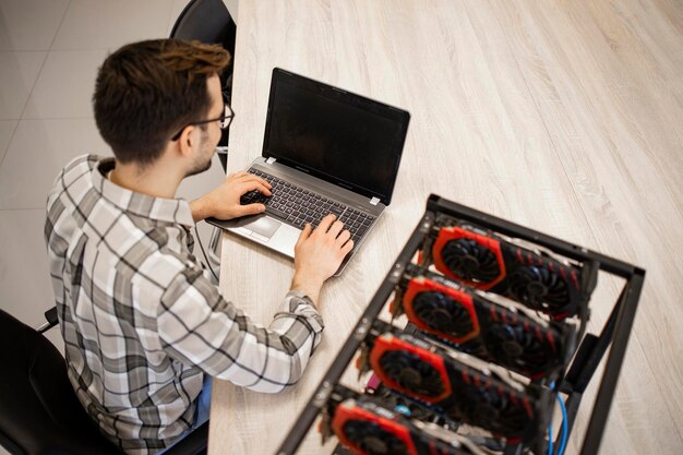 Foto vista superior del programador que trabaja en su plataforma de minería de criptomonedas verificando el valor y las ganancias de bitcoin