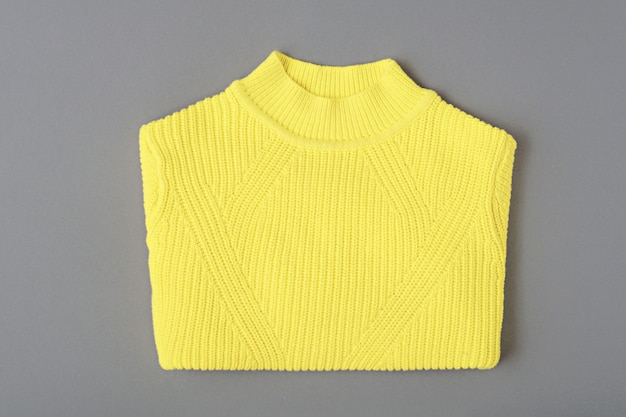 Vista superior de punto suéter amarillo cálido estampado sobre fondo gris