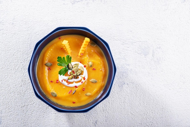 Vista superior puré de sopa de calabaza en plato azul perejil semillas de calabaza sobre fondo blanco platos de otoño copia espacio