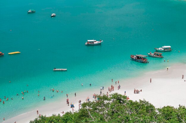 Vista superior para que la gente se relaje en la playa en un resort tropical, los barcos turísticos están parados en la orilla