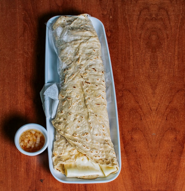 Foto vista superior de quesillo nicaragüense en un plato servido en una mesa de madera delicioso quesillo tradicional nicaragüense servido en una mesa de madera vista de un quesillo nicaragüense servido en una mesa