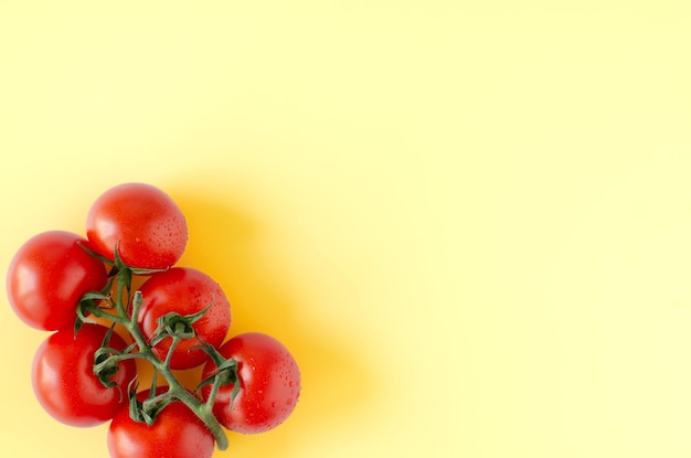 Vista superior del racimo de tomates frescos sobre fondo amarillo