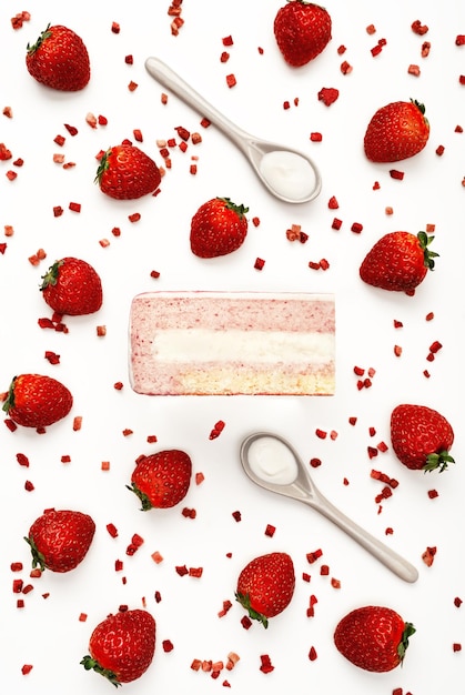 Foto vista superior de una rebanada de pastel de fresa con capas e ingredientes de la receta dispuestos sobre un fondo blanco