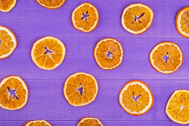 vista superior de las rebanadas de naranja secas aisladas sobre un fondo de madera púrpura