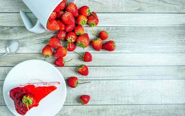 Vista superior de rebanadas de pastel de fresa frescas en un plato y fruta de fresas rojas frescas en un azul