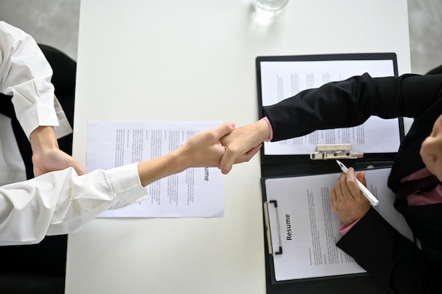 Vista superior de un reclutador estrechando la mano de un joven candidato después de una entrevista de trabajo