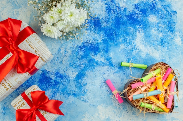 Vista superior de los regalos navideños, desplace los papeles de deseo en una caja en forma de corazón sobre fondo azul espacio libre