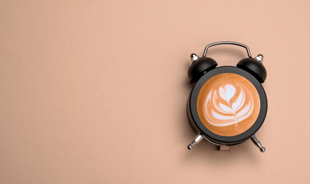 Vista superior reloj de alarma plano con café en él Beige fondo marrón claro espacio de copia collage de café de arte minimalista