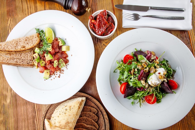 Vista superior de sabrosa ensalada verde con tomate y remolacha y tartar de ternera con aguacate y lima. Deliciosa cena. Comida sana. Plana pone comida. Vista desde arriba