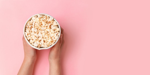 Vista superior de sabrosas palomitas de maíz saladas sobre un fondo rosa