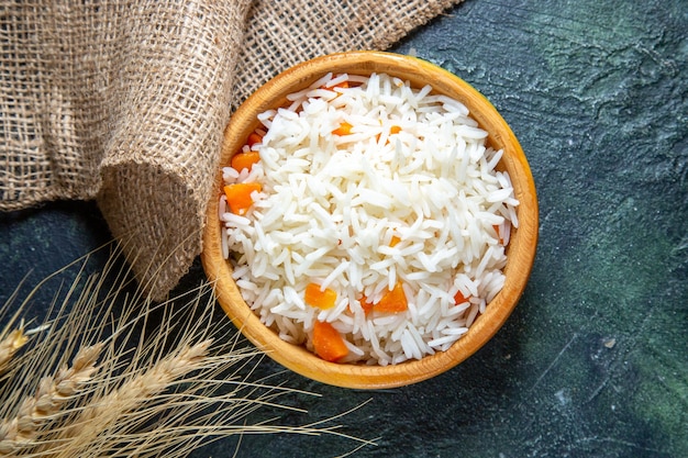 Vista superior sabroso arroz hervido dentro de un plato pequeño en el escritorio oscuro