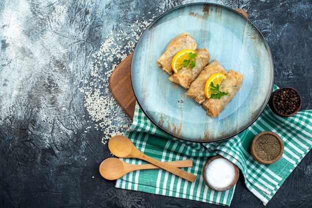 Vista superior sabroso repollo dolma con rodajas de limón y condimentos sobre fondo gris cocina cena color hielo plato pan comida caloría