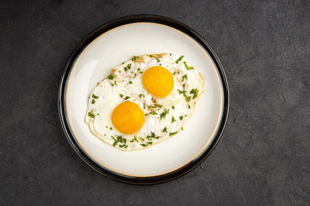 Vista superior sabrosos huevos revueltos dentro de la placa sobre fondo oscuro tortilla comida desayuno mañana almuerzo pan té comida