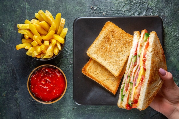 Vista superior sabrosos sándwiches de jamón con tostadas dentro de la placa sobre una superficie oscura