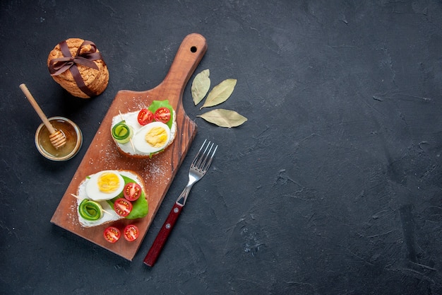 Vista superior sabrosos sándwiches con tomates y huevos en la tabla de cortar fondo oscuro tostada comida pan sándwich de hamburguesa almuerzo comida