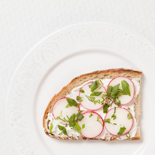 Vista superior de sándwich integral con rábano orgánico y queso crema en plato blanco