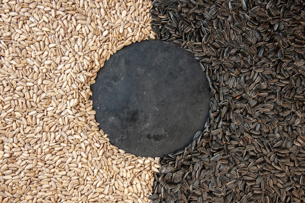 Vista superior de semillas de girasol negras con semillas peladas sobre fondo oscuro Foto de semilla de cips de color de aceite de bocadillo de maíz