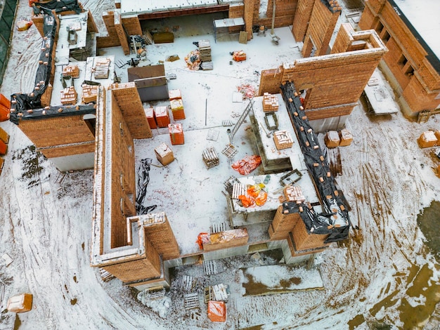 Foto vista superior del sitio de construcción construcción de una casa de ladrillo rojo edificio en invierno toma detallada del sitio de construcción nieve en el sitio de construcción
