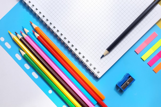 Vista superior sobre cadernos, lápis, apontador em um fundo azul. Volta ao conceito de escola
