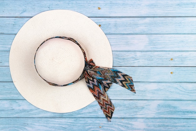 Vista superior de un sombrero de paja blanco acostado sobre un fondo de madera azul. El concepto de vacaciones de verano