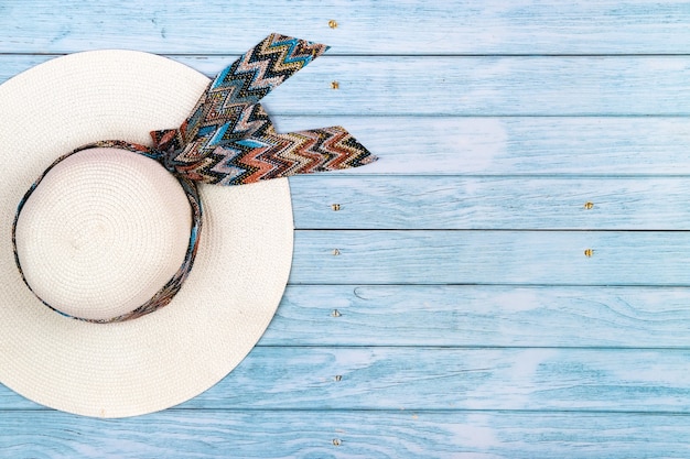 Foto vista superior de un sombrero de paja blanco acostado sobre un fondo de madera azul. el concepto de vacaciones de verano.