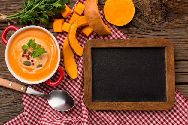 Foto vista superior de la sopa de calabaza de invierno con pizarra