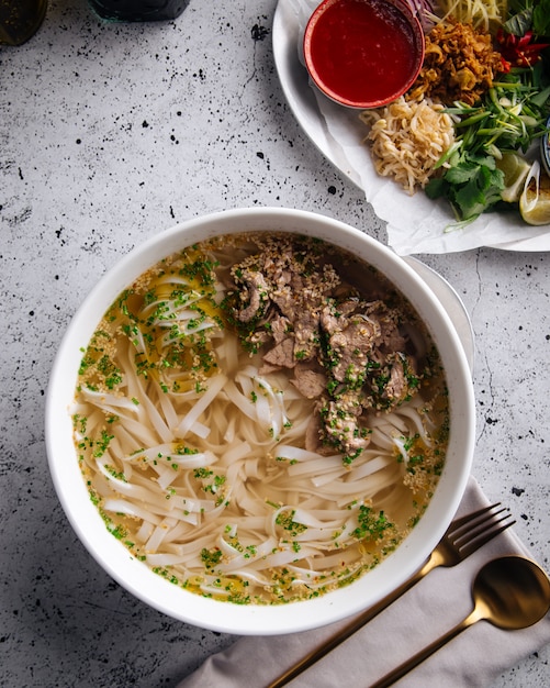 Vista superior de la sopa pho bo vietnamita con fideos de carne y arroz en la mesa servida