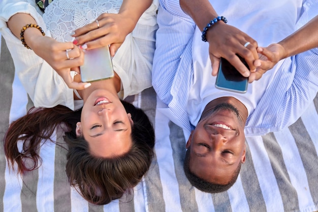 Vista superior sorrindo jovem casal olhando para telas de smartphones