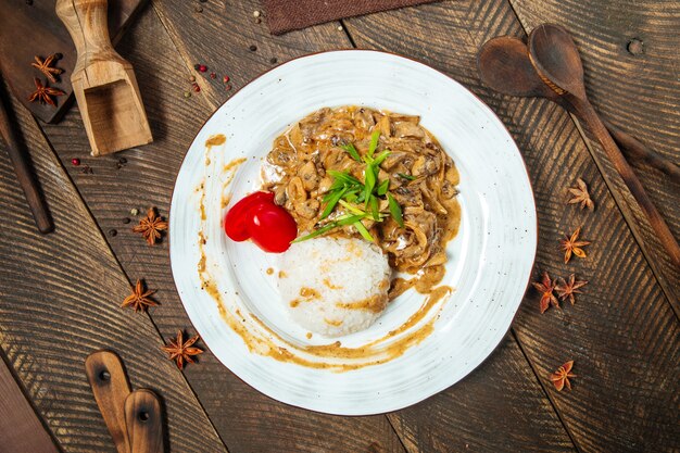 Vista superior de stroganoff de ternera con arroz en una mesa de madera