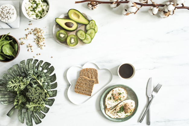 La vista superior de super comida en la mesa de mármol blanco. Endecha plana. Ingredientes vegetales variados y comida sana para vegetarianos. Mesa de desayuno. Copie el espacio. Plantilla.