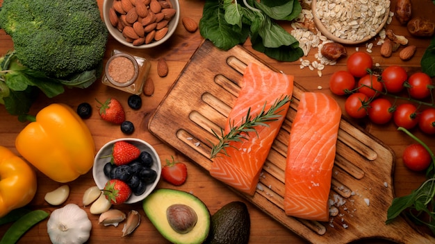 Vista superior del surtido de alimentos saludables con salmón, frutas, verduras y semillas en la mesa rústica