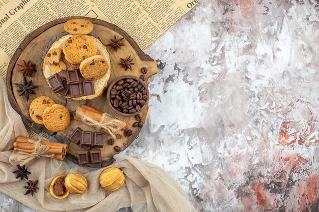 Vista superior de tableros de madera con tazón de galletas con granos de café tostados, palitos de canela y chocolate en la mesa con lugar para copiar