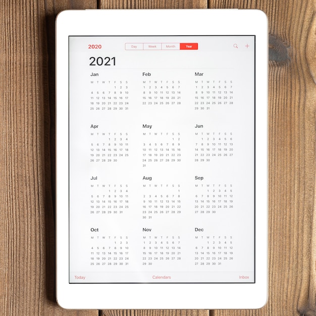 Vista superior de la tableta con un calendario abierto para el año 2021 en una mesa de tablas de madera