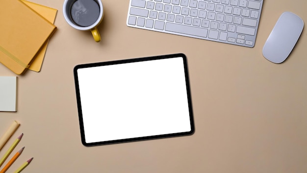 Vista superior tableta digital portátil taza de café y teclado inalámbrico sobre fondo beige