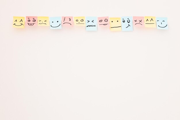 Foto vista superior de tarjetas de papel con varios emoticonos sobre fondo blanco.