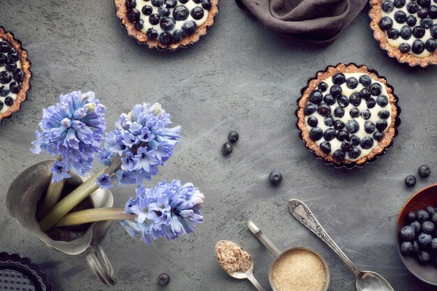 Vista superior de tartas de arándanos integrales con crema de vainilla en la oscuridad