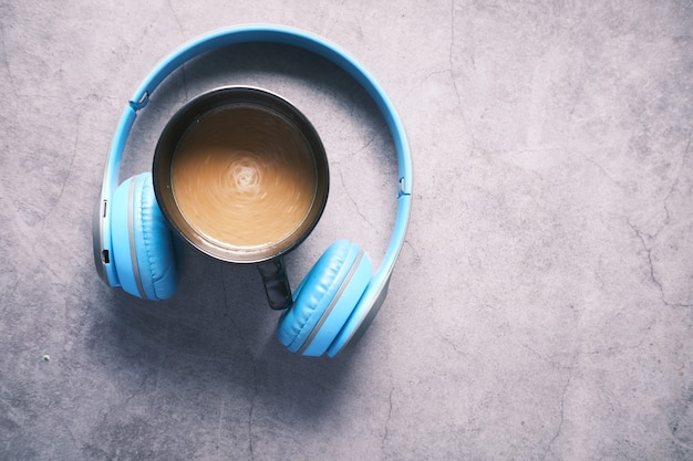 Vista superior de la taza de café y auriculares sobre fondo negro