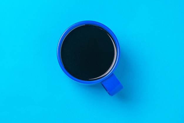 Vista superior de una taza de café azul sobre una superficie azul. Una bebida vigorizante popular.