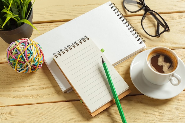 Vista superior. Taza de café con café. pluma poniendo en el cuaderno en blanco.