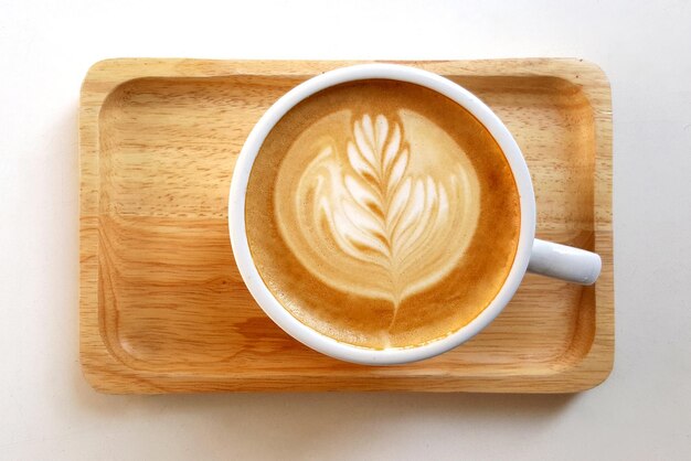 Vista superior de una taza de café latte en un plato de madera