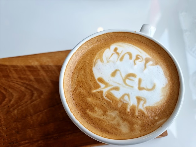 Vista superior de una taza de café con leche caliente arte palabra feliz año nuevo