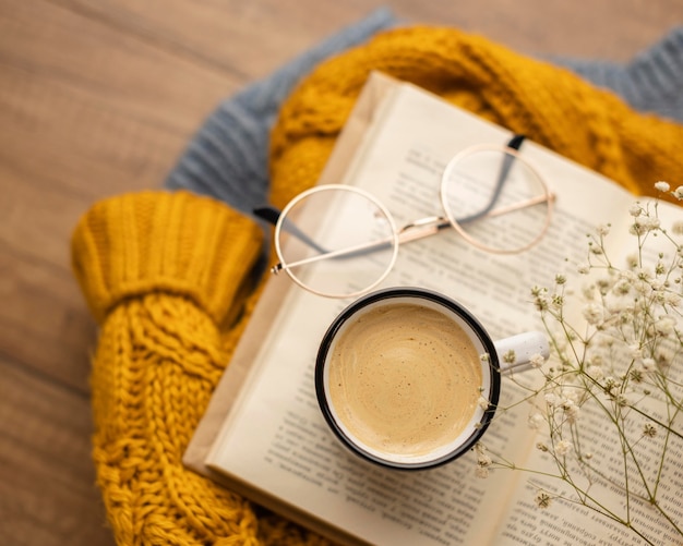 Vista superior de la taza de café en el libro con gafas y suéter