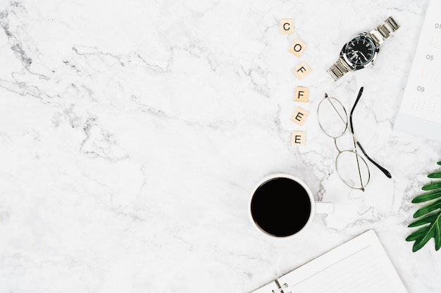 Vista superior de la taza de café negro con gafas y reloj en el escritorio con espacio de copia