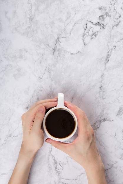 vista superior de una taza de café negro sostenida por las manos