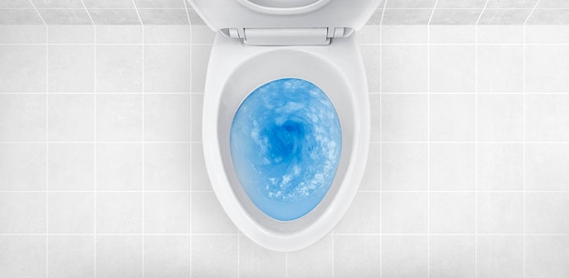 Vista superior de la taza del inodoro con detergente azul que se enjuaga